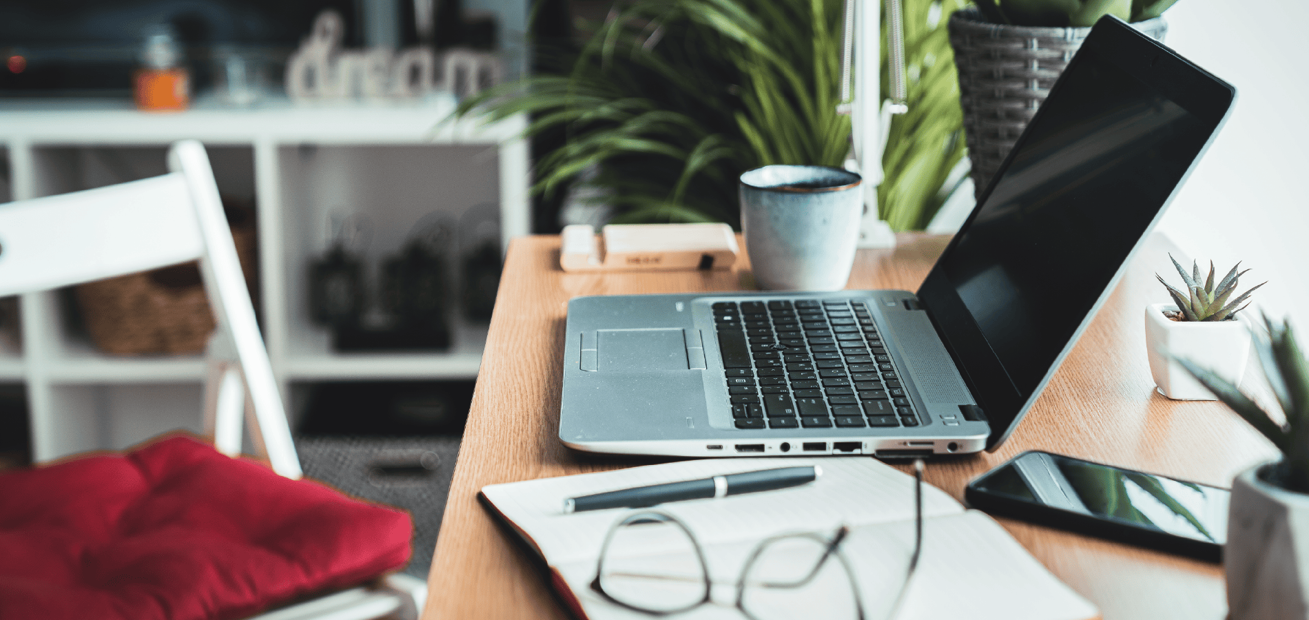 Laptop, notebook, and glasses on desk